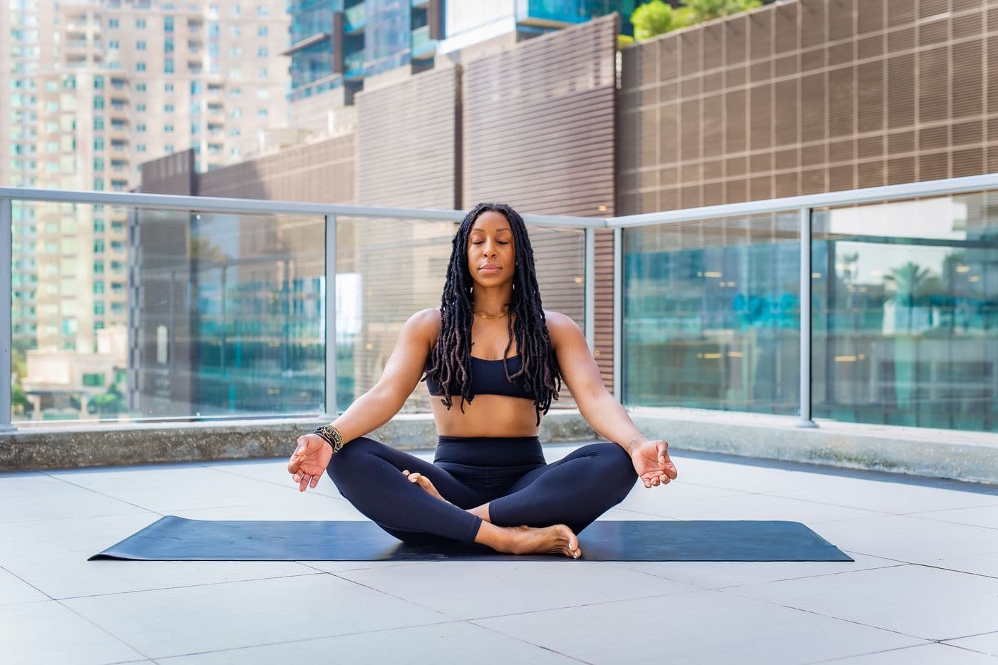 Woman meditating on a city balcony