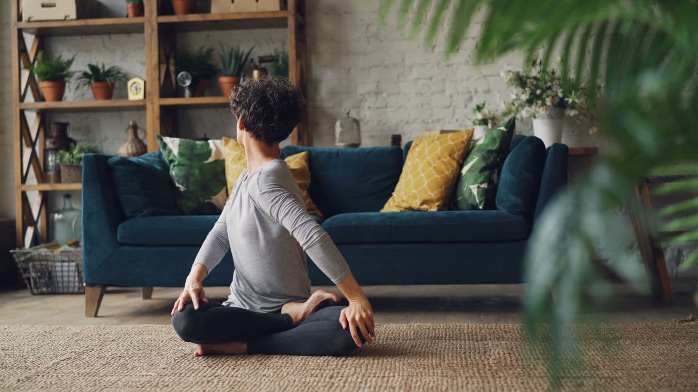 Woman practising yoga at home among plants