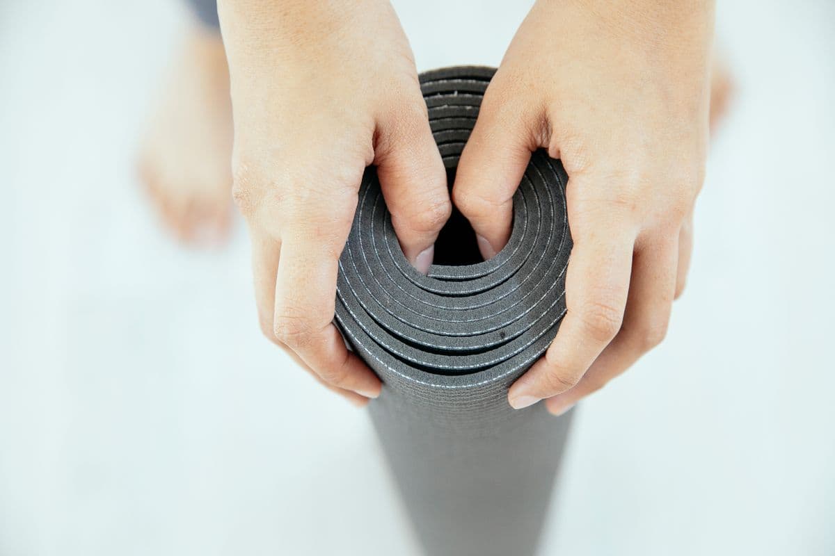 Hands rolling a yoga mat